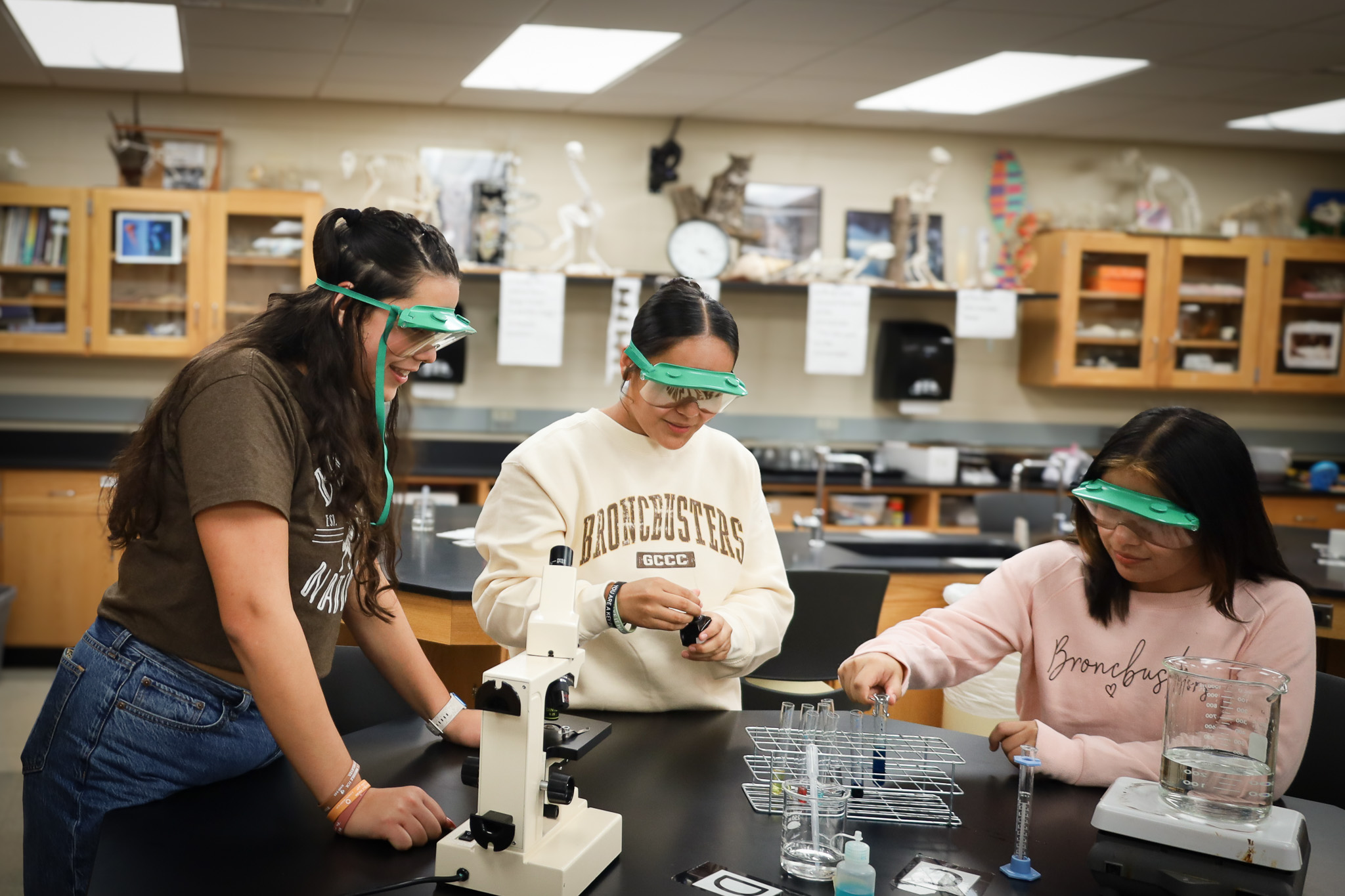 three biology students wearing goggles.