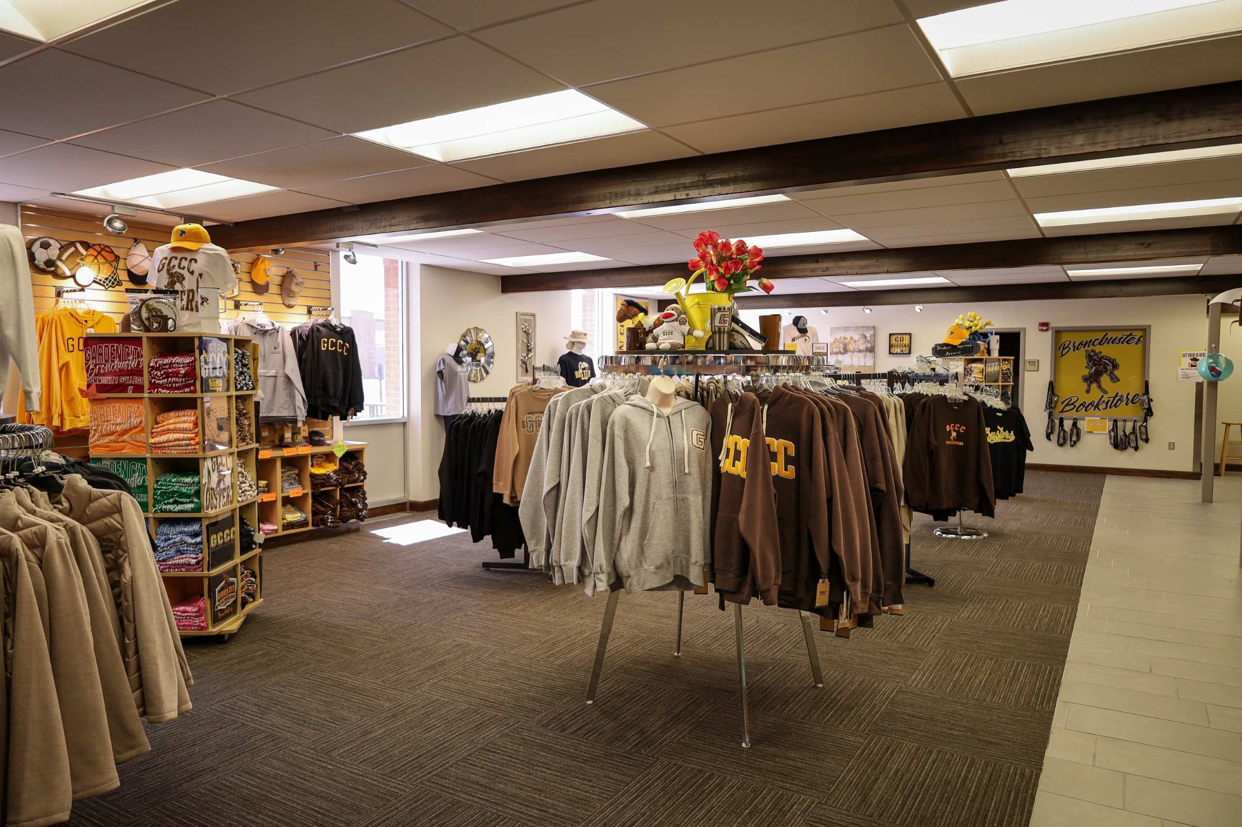Generating response Copilot said: Campus bookstore displaying college-branded apparel, gifts, and merchandise on clothing racks and shelves.